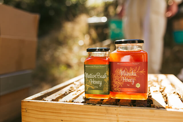Jars of MVH Native Bush Honey and MVH Manuka Honey on top of a beehive