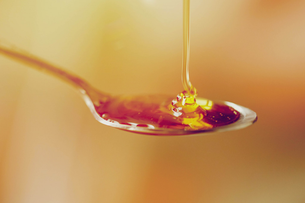 honey being drizzled onto a teaspoon